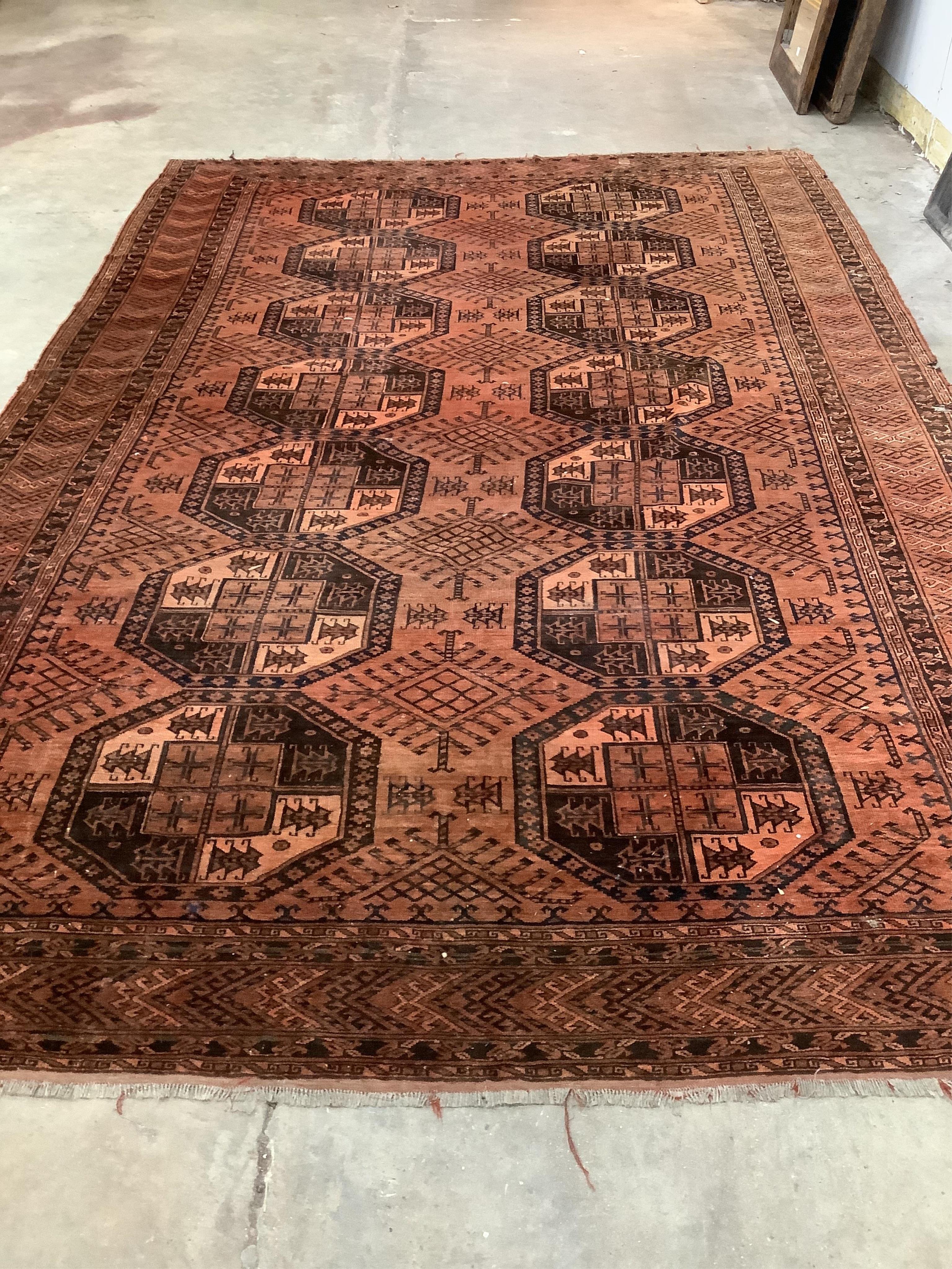 An Afghan rust ground carpet, 400 x 260cm. Condition - poor, damage to border